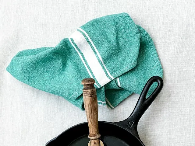 A cast iron skillet with a spatula on a white counter